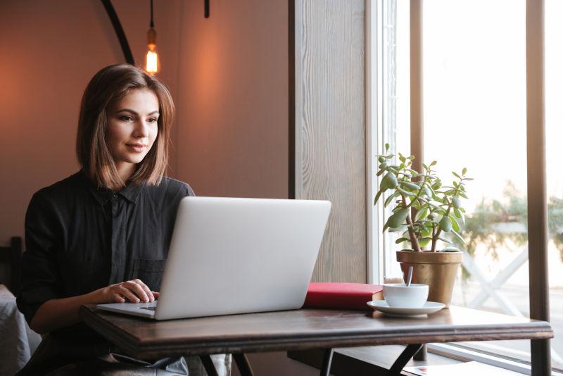 漂亮的女士坐在咖啡馆里看笔记本电脑