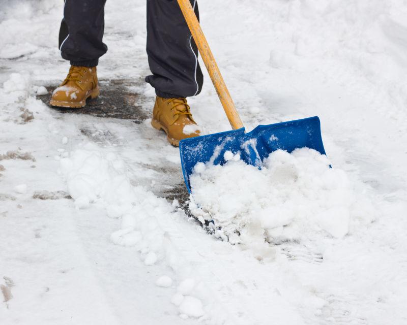 男子用铁铲清扫地上的积雪