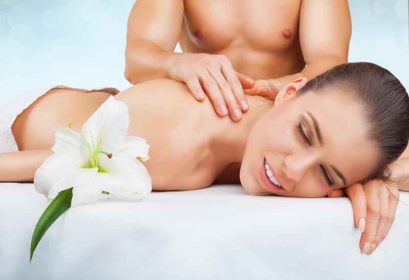 美丽的女人闭着眼睛在浅浅的背景下接受按摩