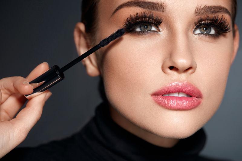 拿着黑色睫毛膏涂睫毛的美女