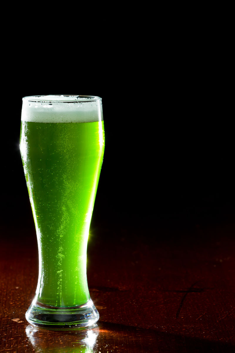 木桌上装着绿色啤酒的透明杯子