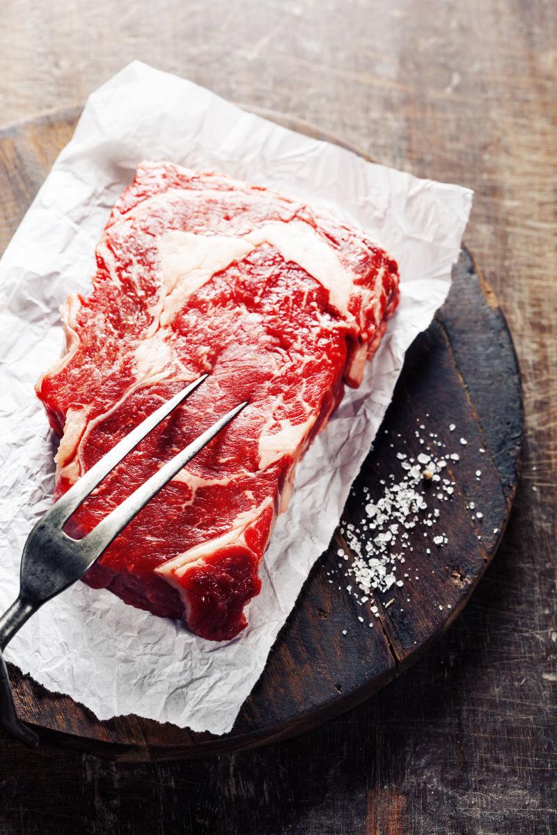 木桌上的生牛排和叉子