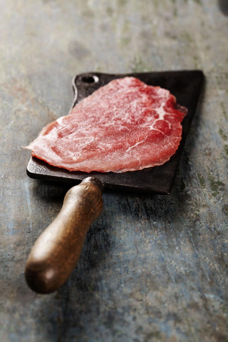 老式的切肉刀和牛肉在黑暗的背景里