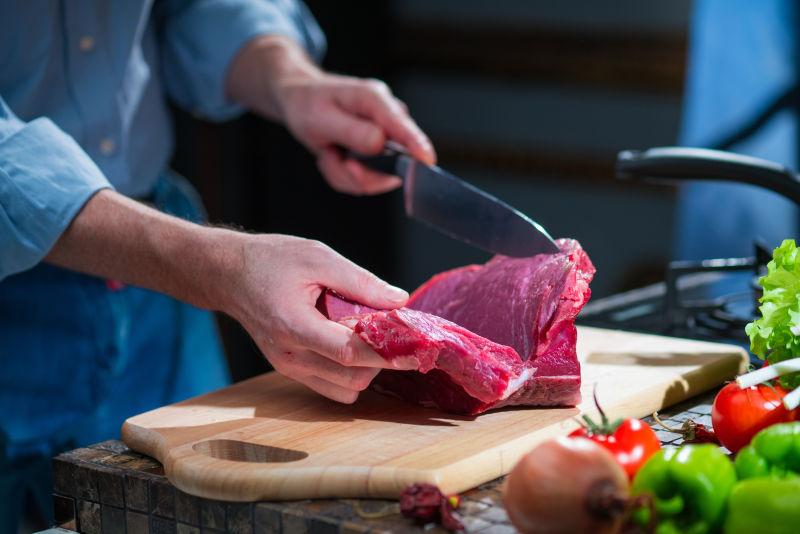 厨房里的人把一块肉切成两半