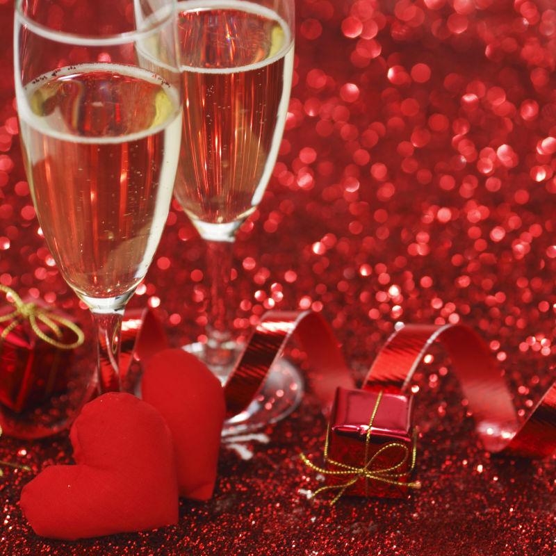 红光闪闪背景下的香槟和礼物