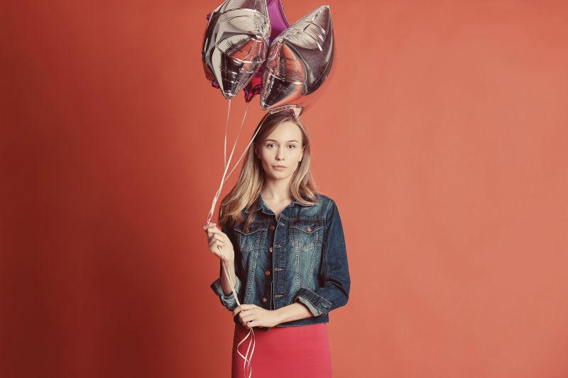 牛仔外套的金发美女拿着气球