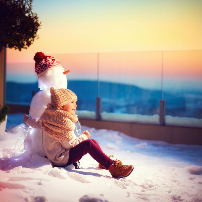 和雪人一起看风景的小男孩