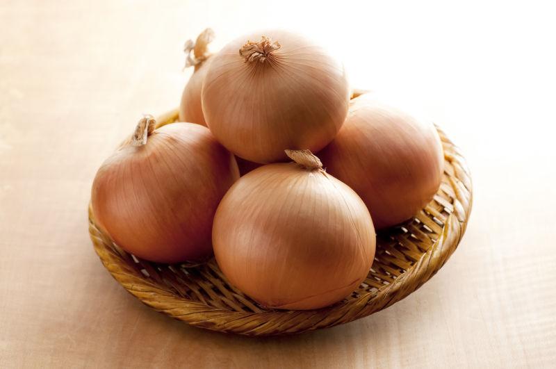 木桌上竹篮里的黄色洋葱头