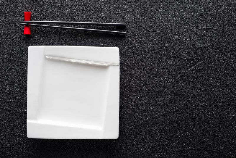 黑色花纹桌面上的白色碗碟和筷子