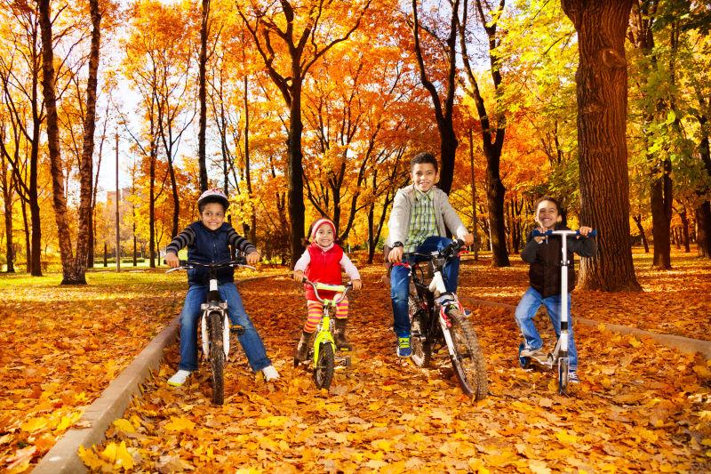 十月秋天的枫叶公园里自行车男孩女孩组