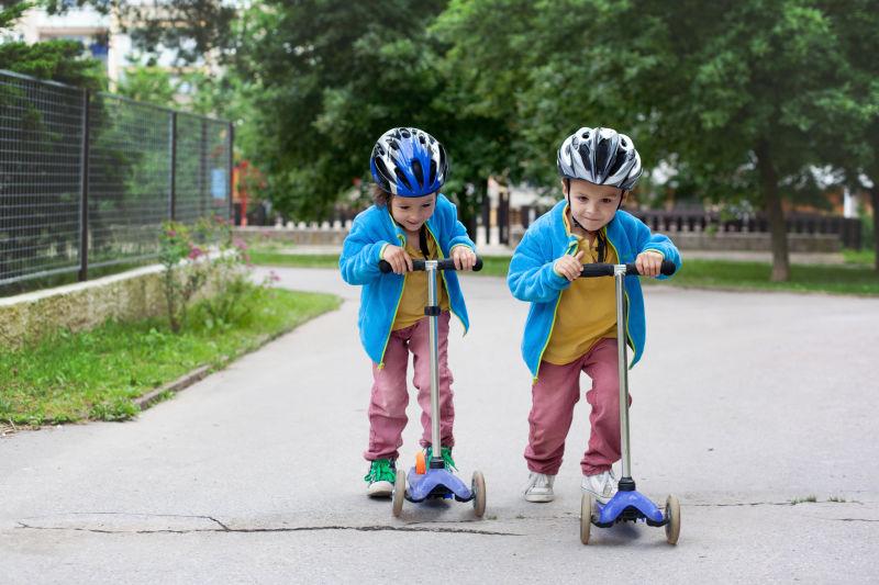 两个可爱的男孩骑滑板车