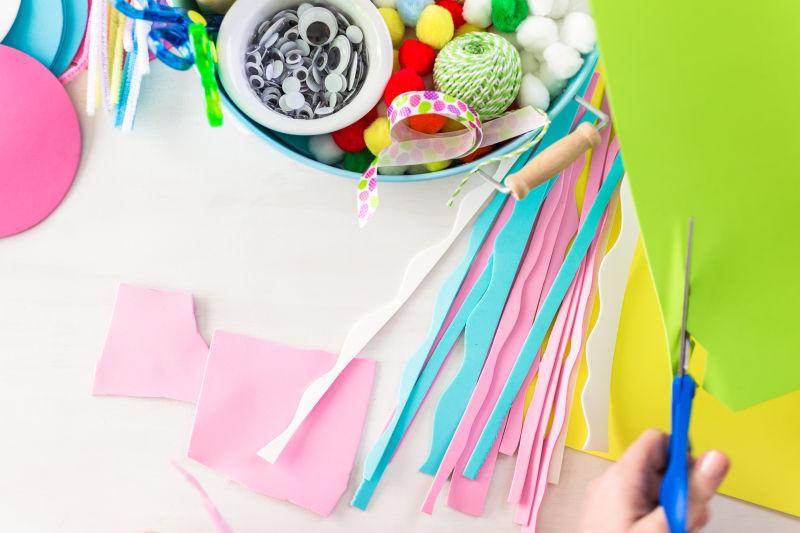 桌子前正在裁剪彩色工艺纸的孩子