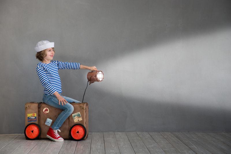 坐在旅行箱上的可爱的孩子