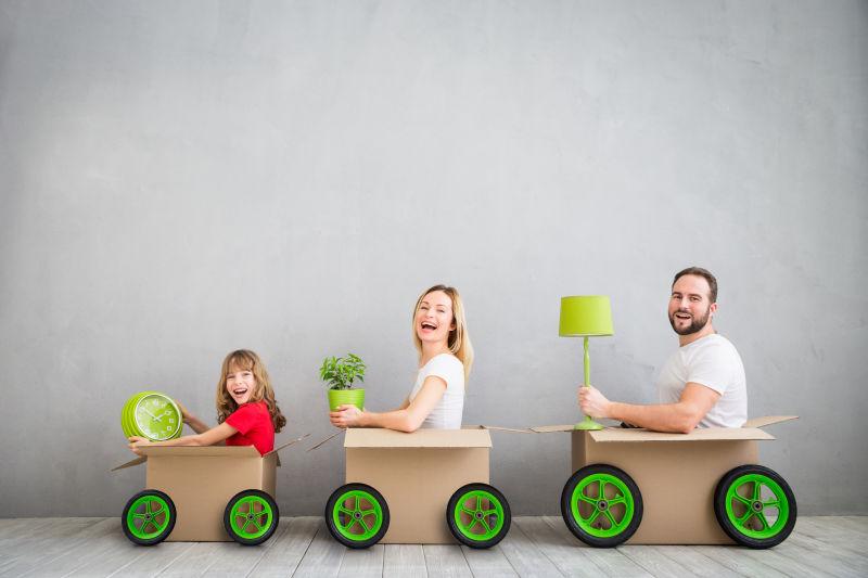 灰色背景下坐在纸箱里的一家三口