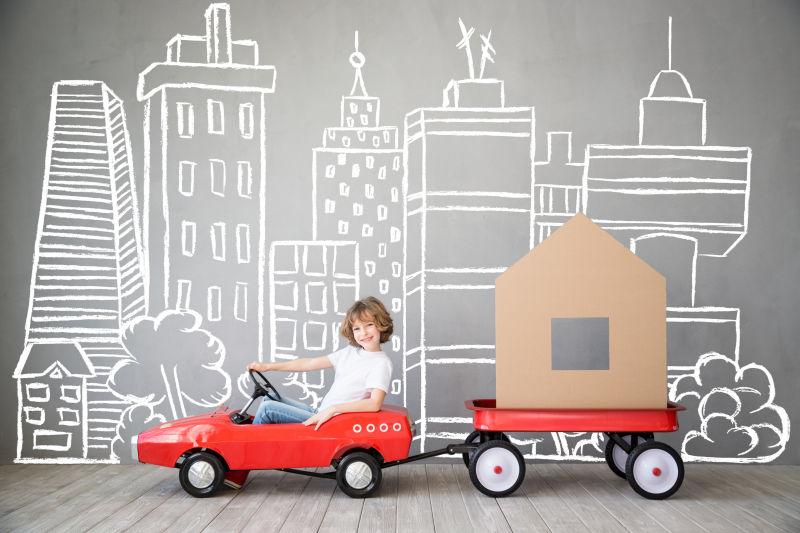 在高楼大厦之间开着小汽车搬家的可爱的孩子