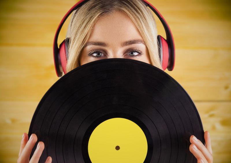 戴耳机的美女拿着唱片在黄色背景下