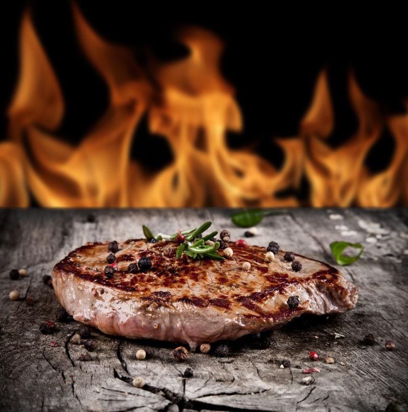 火焰背景上放在木板上美味的烤牛排