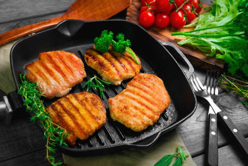 黑色煎锅里的四份烤猪排