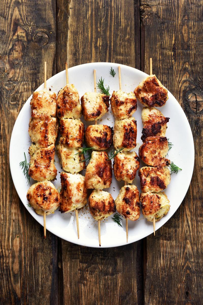 木桌盘子上的烤鸡肉串