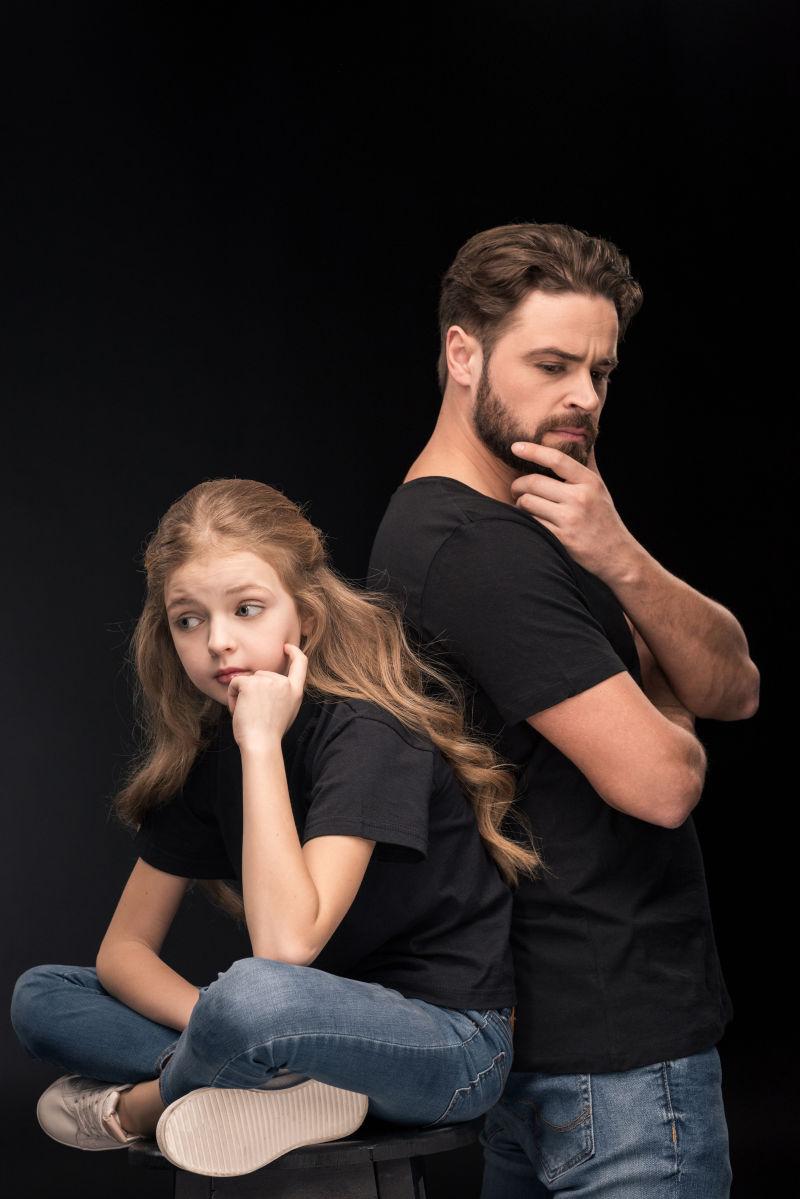 可爱的沉思女儿和忧郁的父亲背靠背