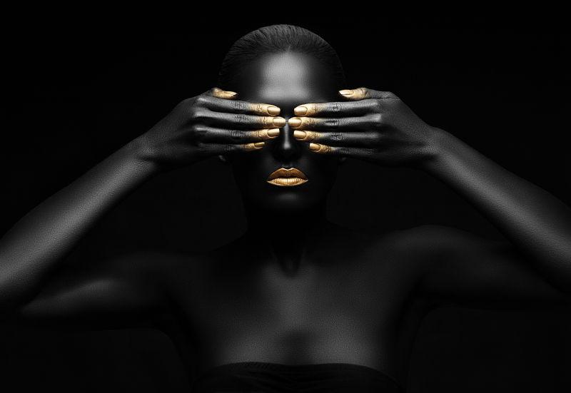 黑色背景上一个全身涂满黑色颜料的黑人用手遮住眼睛