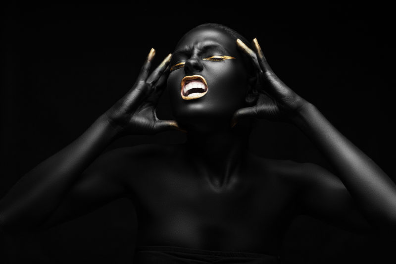 黑色背景上一个全身涂满黑色颜料的黑人美女正在尖叫