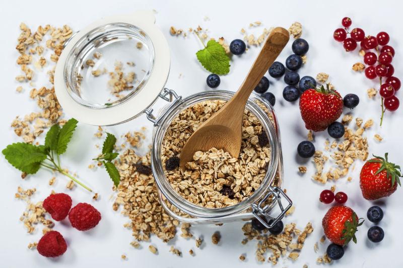 白色桌上散落的浆果和有燕麦片的早餐