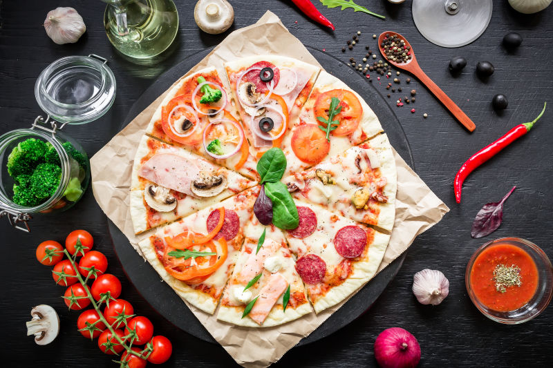 桌子上的披萨饼与配料蔬菜