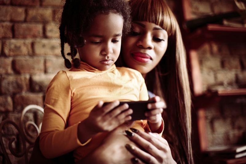 母亲抱着女儿玩手机