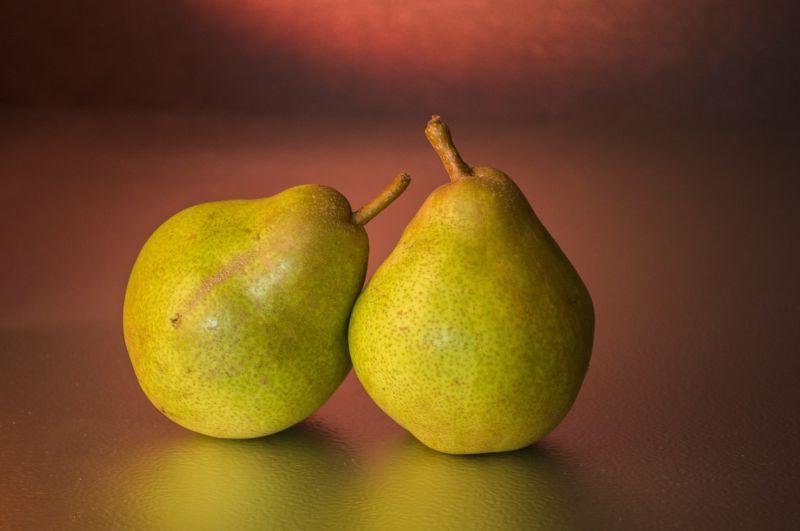 暗红色背景下桌上的青黄色的梨子
