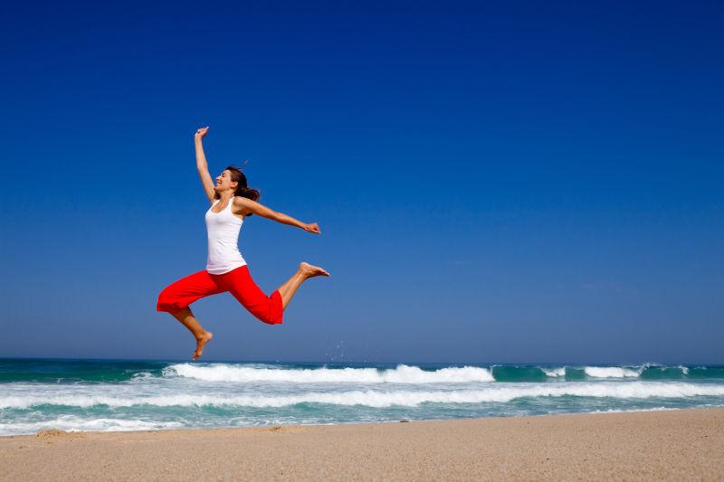 海滩边跳跃的红裤子美女