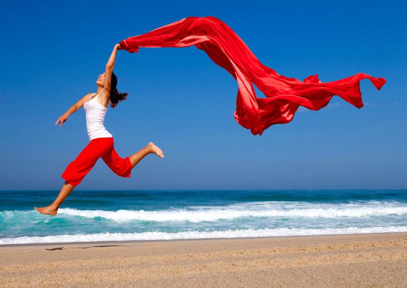 海滩上的美女挥舞着红色的丝带