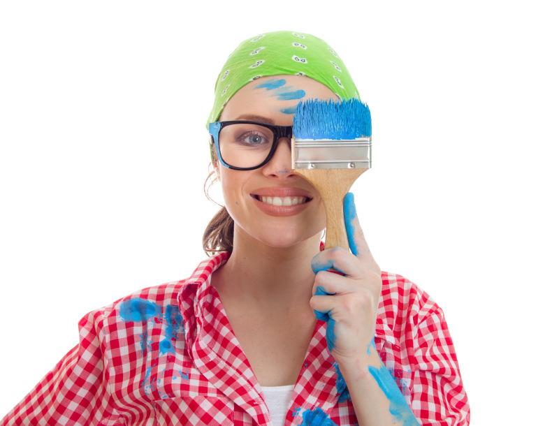 美女油漆工用油漆刷遮住自己的眼镜