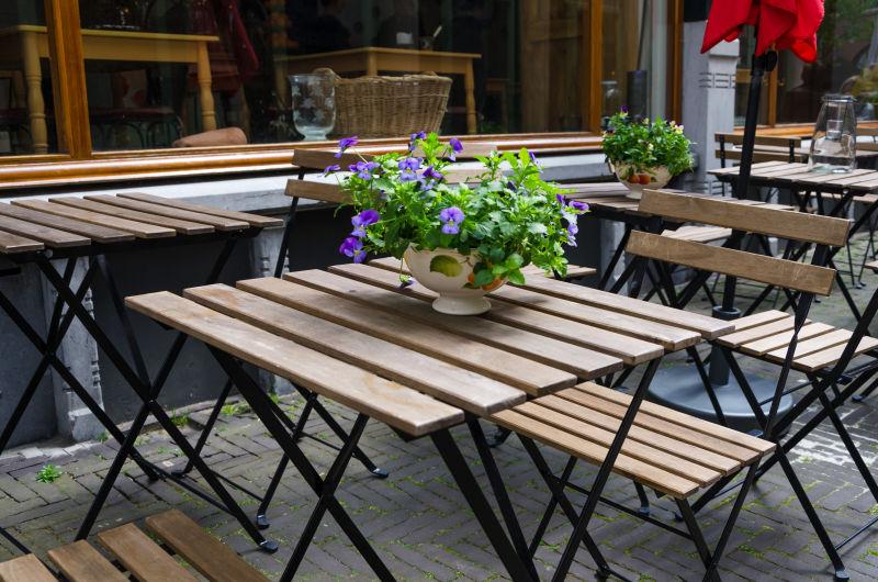 咖啡馆外的木质餐桌上放着一盆美丽的鲜花