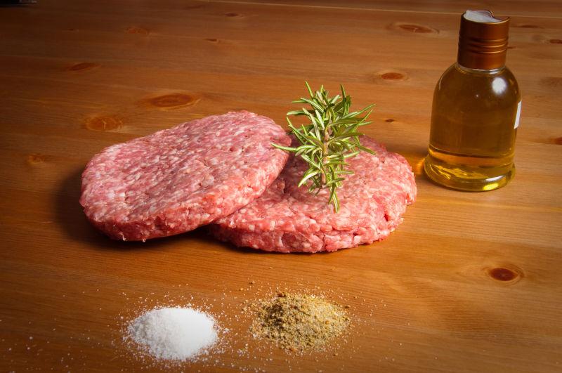 桌子上的肉片和迷迭香还有调味品