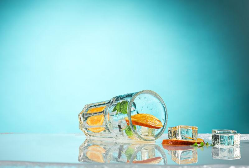 蓝色背景上倒下的加冰柠檬水