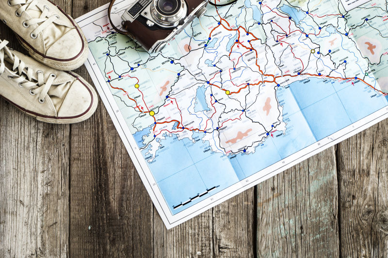 木桌上的的旅行地图和鞋子相机