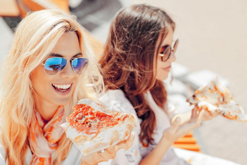 两个年轻妇女在户外吃比萨饼