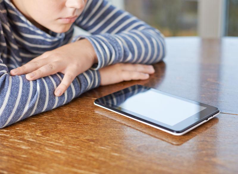 坐在桌前看平板电脑的小孩