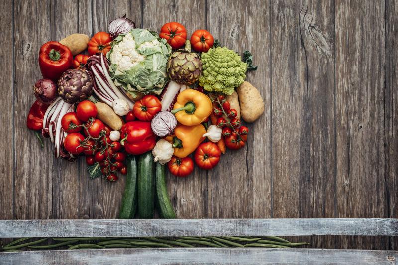 新鲜的有机蔬菜在五颜六色的木桌上制成的郁郁葱葱的树