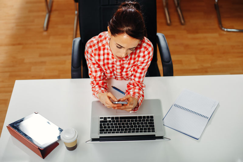 在电脑前玩手机的美女