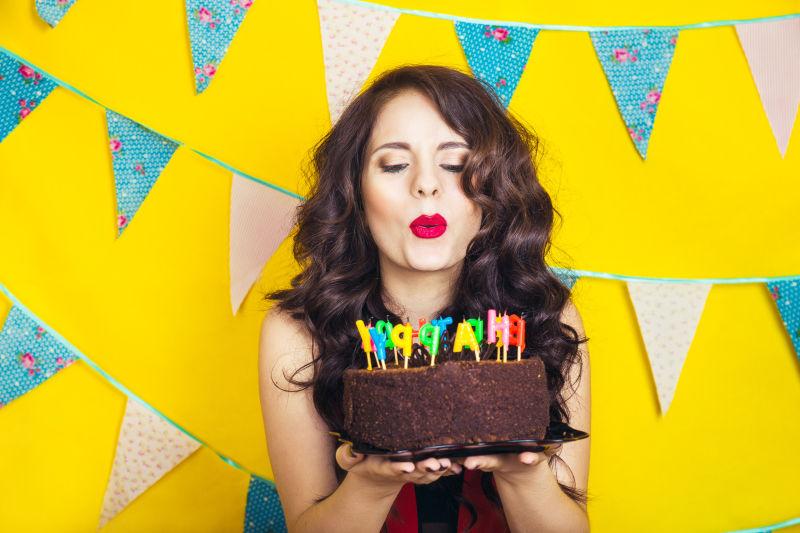 美丽的高加索女孩在她的蛋糕上点燃蜡烛