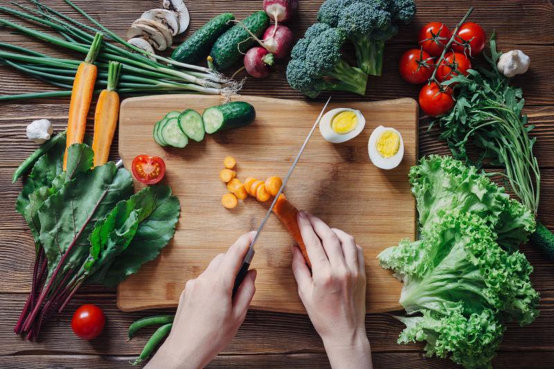 木桌上正在料理中的胡萝卜和各种新鲜蔬菜