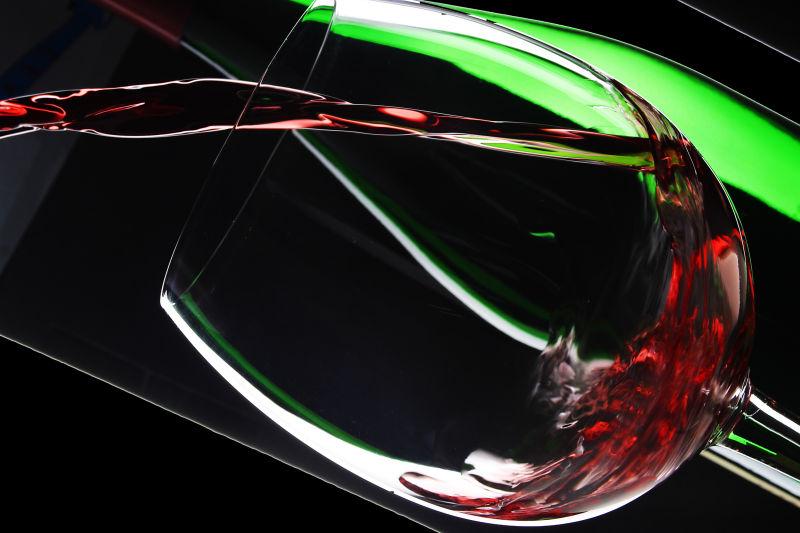 黑色背景下把葡萄酒倒进玻璃杯