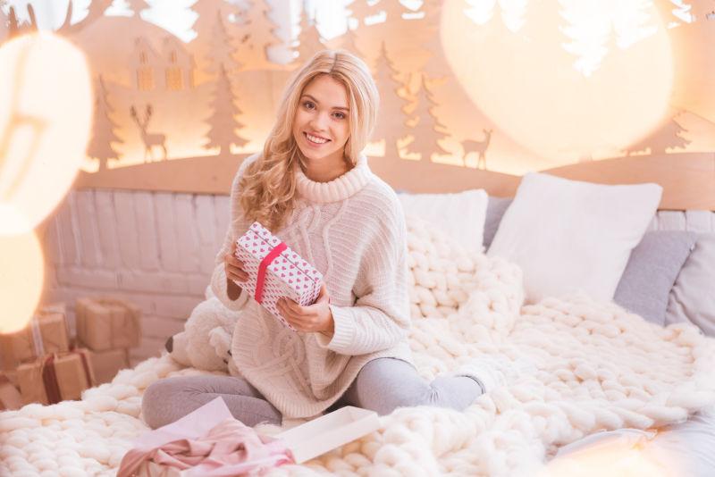 坐在床上的美女拿着礼物盒