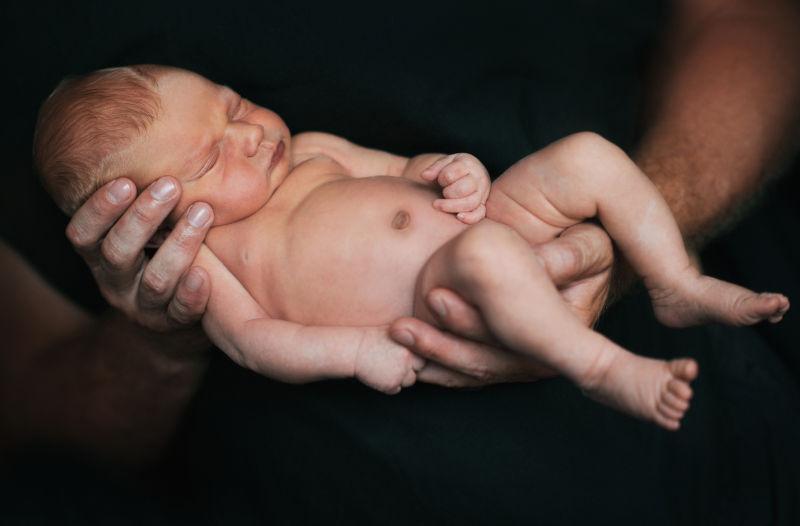 黑色背景中抱着新生儿的爸爸