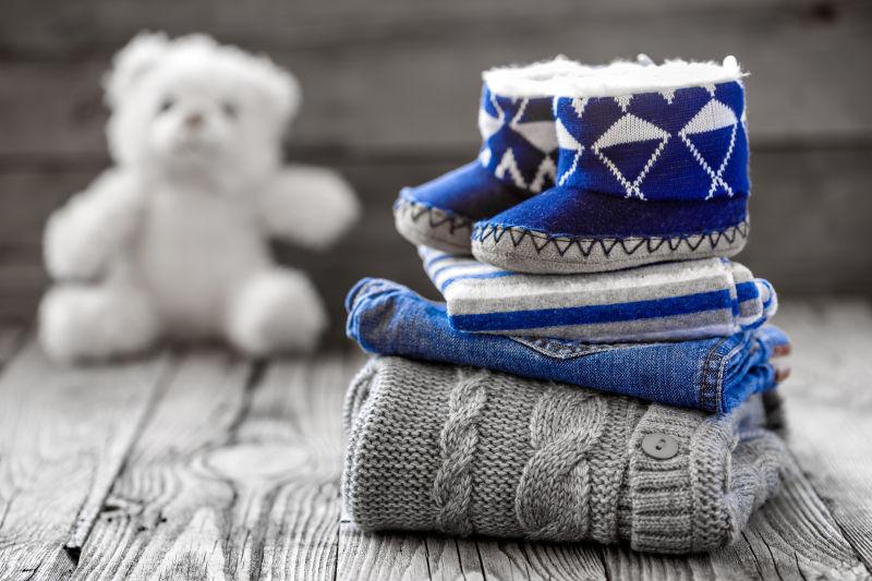 老木桌上婴儿的鞋子和服装