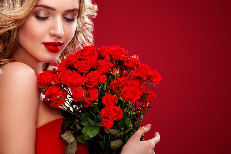 红色背景中金发女人捧着一束红玫瑰