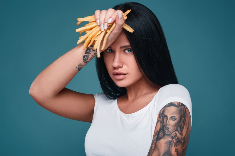 手拿薯条的美丽纹身女孩