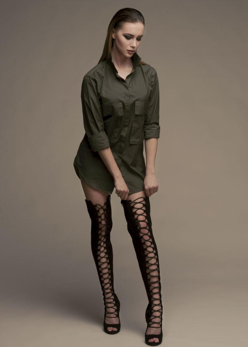 单色背景上正在穿靴子的时尚美女